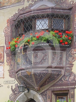 View of the facade of a medieval house with geraniums at the window