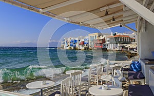 View of the famous pictorial Little Venice in Mykonos island. Splashing waves over bars and restaurants of old town.