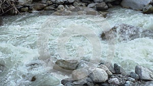 View of a fast flowing mountain river closeup. The camera monitors the movement of water.