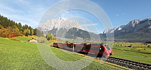 View of a fast train traveling through green fields with magnificent Mountain Zugspitze in the background