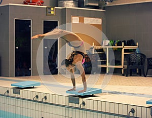 View of a female diver diving into the pool. standing on arms with legs up