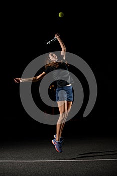 view of female tennis player with tennis racket in her hand bouncing and hitting the tennis ball.