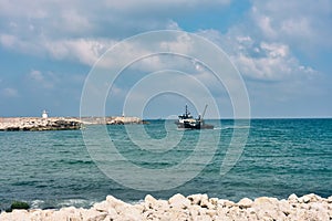 View of a fishing boat returning from the sea to land at sunset and a view of the small harbor,