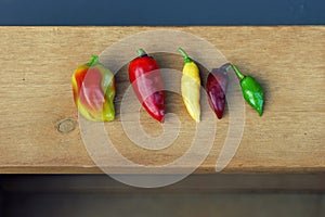 View of five different homegrown chilies on a wood