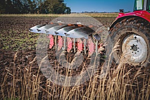 View of a five furrow plough at work behind a red tractor