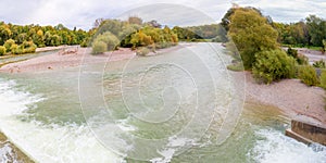 View from flaucher bridge to floodplain isar river munich with shrubbery and trees in autumn