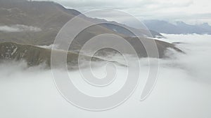 The view of the flight from the drone over the clouds among the mountains