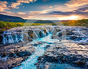 View from flying drone. Exciting summer sunrise on Bruarfoss Waterfall, secluded spot with cascading blue waters. Impressive morni