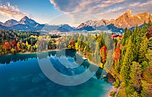 View from flying drone. Majestic morning scene of Urisee lake. Fabulous autumn view of Reutte town, Austria, Europe. Fantastic sun