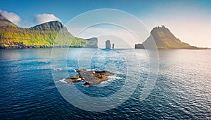 View from flying drone. Misty summer scene of Faroe Islands and Tindholmur cliffs on background. Splendid morning view of Vagar is