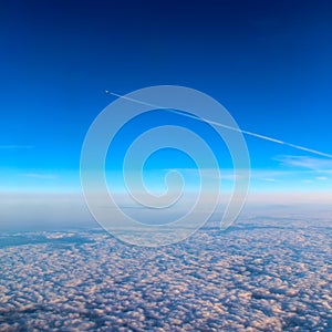 View of a flying plane from another plane, below the clouds