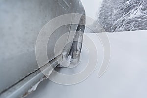 View focused on the car tire during in motion on snowy rural road during snowfall.