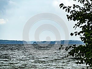 View of the forest lake with a white sail in the distance, lake Uvildy photo