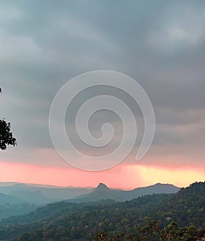 a view of forest in and orange sunset , a view from munnar kerla india photo