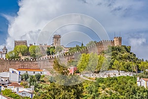 View of the fortress and Luso Roman castle of Ã“bidos, with buildings of Portuguese vernacular architecture and sky with clouds,