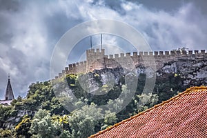 View of the fortress and Luso Roman castle of Ã“bidos, with buildings of Portuguese vernacular architecture and sky with clouds,