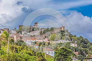 View of the fortress and Luso Roman castle of Ã“bidos, with buildings of Portuguese vernacular architecture and sky with clouds,