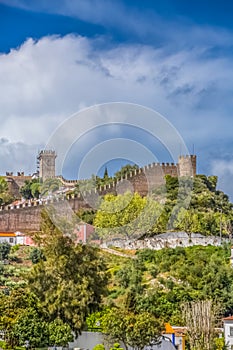 View of the fortress and Luso Roman castle of Ã“bidos, with buildings of Portuguese vernacular architecture and sky with clouds,