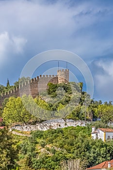 View of the fortress and Luso Roman castle of Ã“bidos, with buildings of Portuguese vernacular architecture and sky with clouds,