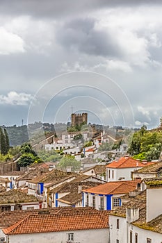 View of the fortress and Luso Roman castle of Ã“bidos, with buildings of Portuguese vernacular architecture and sky with clouds,