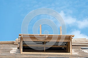 View of the frame of a new wooden roof made of thick beams. Repair of a sloping roof in a country house. Construction site on a