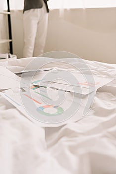 View of freelancer and papers with graphs and charts on white bedding