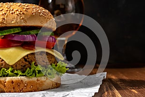 View of fresh tasty burger with glass of beer on wooden rustic table. Food background