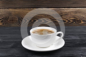 Overhead view of a freshly brewed mug of espresso coffee on rustic wooden background with woodgrain texture. Coffee break style