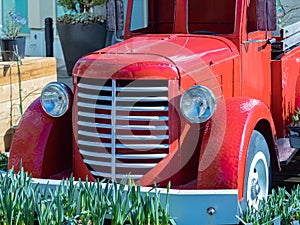 View of the front end of a beautifully restored vintage truck automobile. Old vintage American red pickup car front side