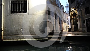 View from the front of gondola of Venice canals and city architecture during ride along one of the canals at twilight