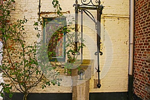 View on front yard of medieval house with ancient water pump, tree, window - Lier Begijnhof, Belgium