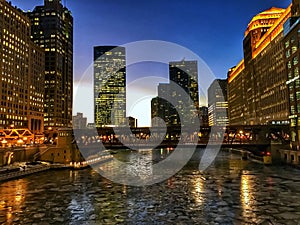 View of frozen Chicago River and elevated track during evening sunset at rush hour.