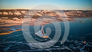 View of the frozen Lake Baikal in January at dawn. Kurma Bay, Cape Uyuga from the air.