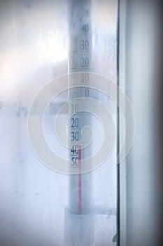 View through frozen window to outdoor thermometer which showing subzero temperature.