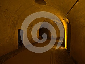 View of gangway in historic castl with paled iron gate and walls illuminated by yellow light in Koblenz, Germany.