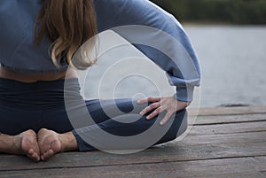 View on a girl with athletic body in blue gym suit is doing yoga exercises in cloudy weather