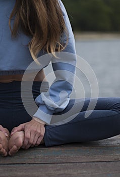 View on a girl with athletic body in blue gym suit is doing yoga exercises in the park