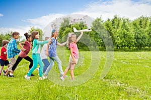 View of girl holding airplane toy and kids behind