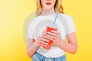 View of girl holding drink in disposable cup Isolated On yellow