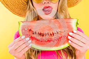 View of girl sticking tongue out and holding watermelon On yellow