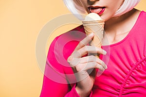 View of girl in white wig eating ice cream, isolated on yellow