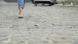 View of girls legs pacing on cobbles.