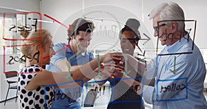 View through glass board of diverse team putting hands together celebrating success