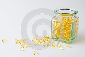 View of glass bottle with yellow evening primrose oil pills on white background, horizontal,