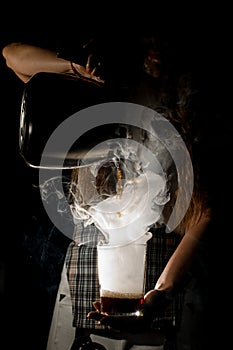 view of glass filled with smoke in which woman pouring drink from coffee pot