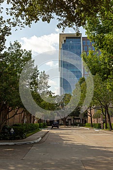 View of a glass skyscraper office building from an in town city street with a white cloud blue sky background photo