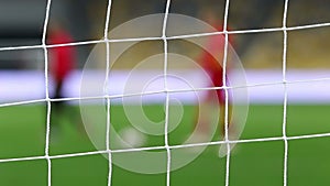 View of goal net with soccer pitch background