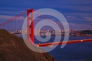 View of the Golden Gate bridge with the Marin Headlands and San Francisco skyline at colorful sunset, California