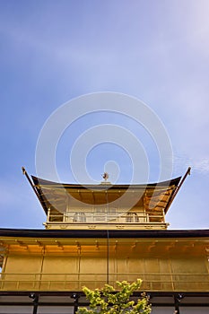 View of golden pavilion of Kinkakuji temple with clouds in blue sunny sky