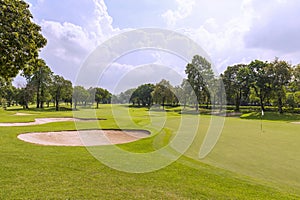 View of a golf course in Thailand with lush green grass, beautiful scenery with sand pits bunker beside the greens and golf holes